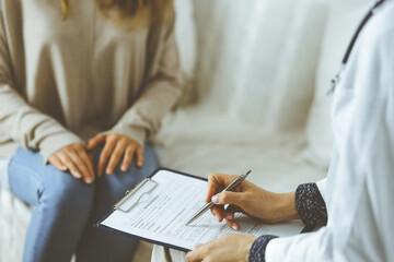 Unknown woman-doctor and patient discussing current health examination while sitting indoors. Stay at home concept during Coronavirus pandemic and self isolation quarantine