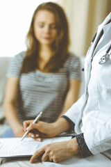 Unknown woman doctor and patient discussing current health examination while sitting in cozy living room. Stay at home concept during Coronavirus pandemic and self isolation quarantine