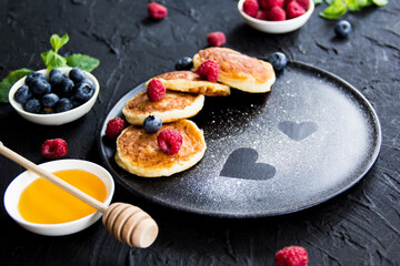 A healthy breakfast of cheese pancakes, berries, and honey. Creative atmospheric decoration