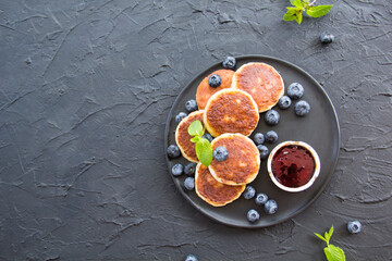 A healthy breakfast of cheese pancakes, berries, and honey. Creative atmospheric decoration