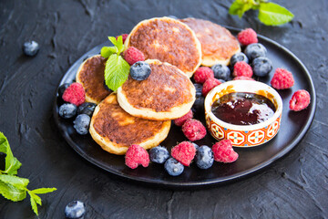 A healthy breakfast of cheese pancakes, berries, and honey. Creative atmospheric decoration