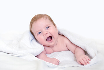 Cute happy 3 month baby boy or girl lying on a white towel. Concept for articles about childhood or advertising for babies