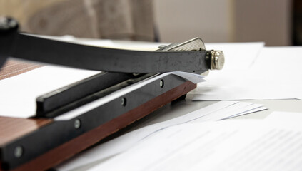 using a Paper cutter or guillotine to make a book in the office. cutting paper on desk.  office...