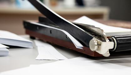 using a Paper cutter or guillotine to make a book in the office. cutting paper on desk.  office...