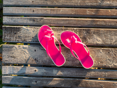 Beach pink bright slippers stand on a wooden platform near the ocean. Close-up of slippers from above. Island Cayo Coco, Cuba.