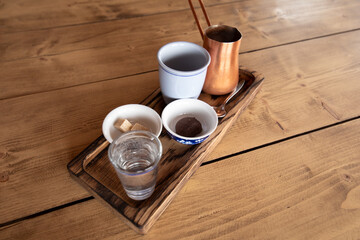Tray with a cup, a copper Turk, sugar and cookies on a wooden table.