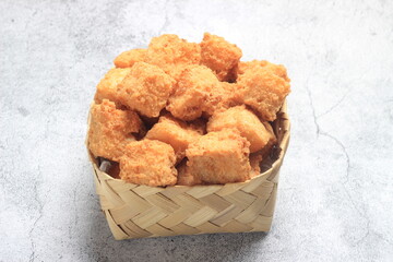 Photo top view, tahu krispi or crispy Tofu  at bamboo bowl, besek under brown abstract marble 
