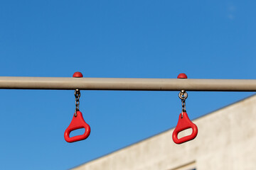 Red handles for a partial grip on a horizontal bar against a blue sky during the day