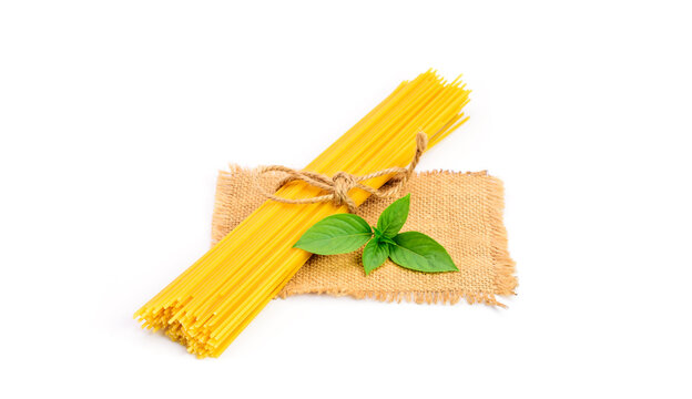 Top view of a bunch of bucatini or perciatelli - pasta, spaghetti with fresh green basil on sackcloth. isolated on a white background