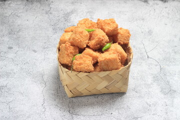 Photo Top View, tahu krispi or crispy Tofu  and green chili at bamboo bowl, besek under brown abstract marble 
