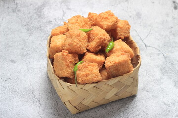 Photo Top View, tahu krispi or crispy Tofu  and green chili at bamboo bowl, besek under brown...