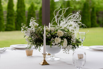 Table centerpiece with white and green floral arrangement in vase.