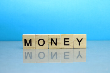 Money word made of wooden blocks on a blue background