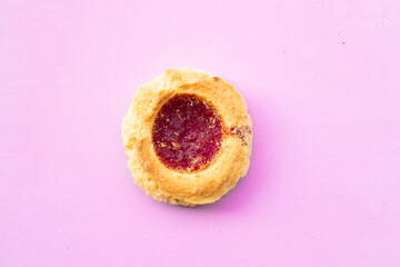 Aerial view of a homemade shortbread cookie with jam on a pink background. Homemade and natural food concept. Horizontal orientation.