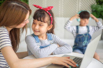 happy loving family. pretty young mother reading a book and drawing to her daughter and son.Mother teach Asian preschool student do homework by reawing by a color.