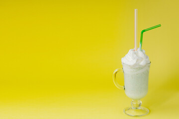 Cold green Peppermint milkshake on a yellow background