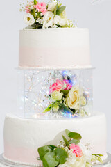Tiered cake for wedding or birthday. Beautiful white and pink festive cake decorated with flowers