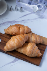 croissant on a brown plate next to a mug of milk on marble background