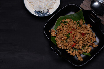 Stir-fried basil with chicken and steamed rice on black background