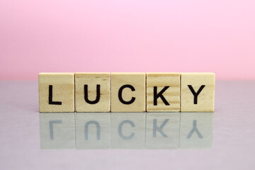 Lucky word made of wooden letters on a pink background