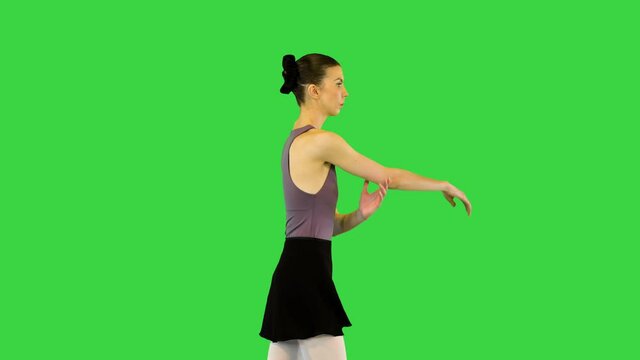 Young ballerina in training clothes walks warming up on a Green Screen, Chroma Key.
