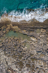Tide pools during low tide. Rocky sea shore with dramatic texture, vertical top view