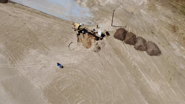 Aerial view of Excavator machine working on the sandy beach preparing it for beach bar
