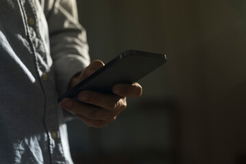 Close-up of man using mobile phone for searching information in internet. Persons hand holding...