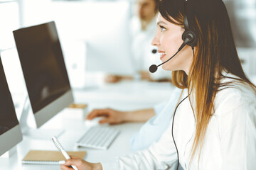 Group of diverse operators at work in call center. Beautiful asian woman sitting in headset at customer service office. Business concept