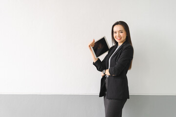 Portrait of a cheerful confident Asian businesswoman in a business suit standing whie using a digital tablet in the business building. Business stock photo