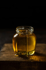 a jar of honey with a honey spoon on a wooden board