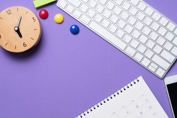 close up of calendar, computer, alarm clock and accessory on the purple table background, planning...