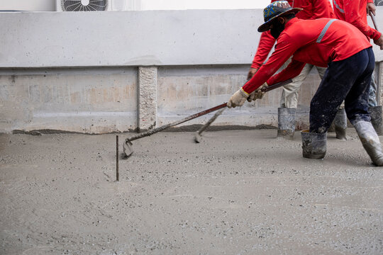 two worker team working wet cement  on floor by use trowel with long Tools spreading poured concrete for reinforce strong street after dry.