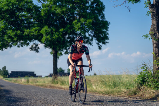 Angle photo of a young woman, pedaling, riding a road bike, on a ride through nature.