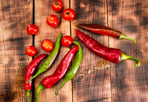 Red and green chili peppers chillies and cherry tomatoes vegetables wooden background, food