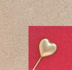 Gold heart on a stick on the right against the background of paper with glitter