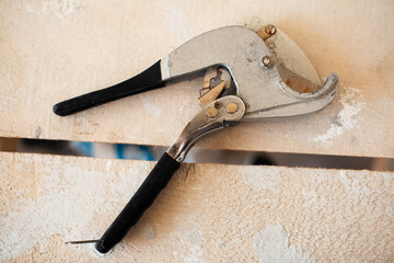 Close-up of plumbing scissors on background of wooden table.