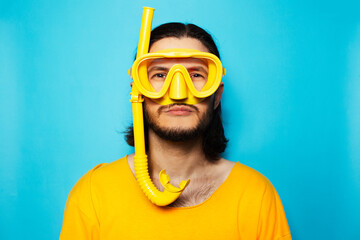 Funny diving man wearing yellow dive equipment on blue background.