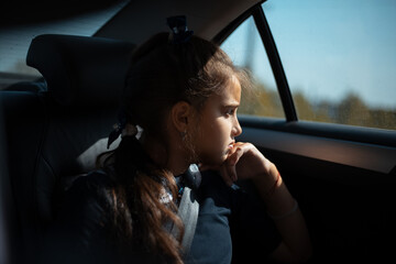 Portrait of teenage girl in the backseat of the car, looking at the window.