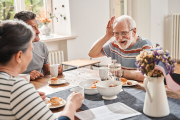 Senior man laughing out loud while speaking with his friends at the retirement house