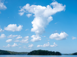 Obraz premium White cloud formation over water and islands covered with trees. Beautiful blue summer sky. Shot in Stockholm archipelago, Sweden, Scandinavia.