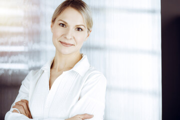 Obraz premium Friendly adult business woman standing straight. Business headshot or portrait in sunny office