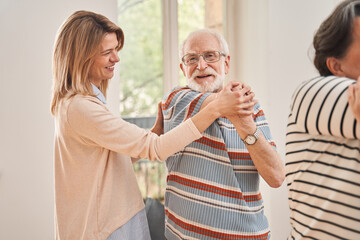 Senior man training yoga and doing morning exercises with help of his caregiver
