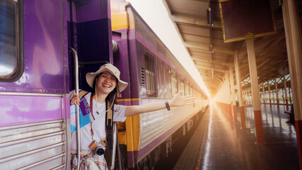 Portrait, Asian Woman Traveller smiling feeling happiness and shoulder backpack with camera, map, on the train at the train station. Active and travel lifestyle concept.