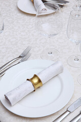 Festive table setting.Napkins made of cotton with brass rings.The concept of holidays.Top view.White tablecloth with a textured pattern.