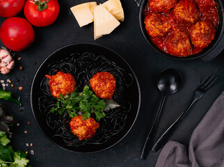Black pasta, spaghetti with Meatballs . in tomato sauce, on a black plate, rustic, horizontal, no people,