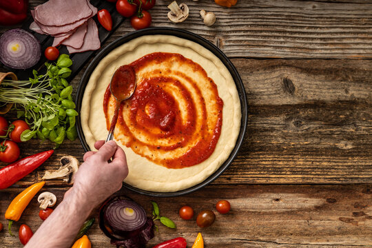 Raw delicious pizza dough with red souce on the wooden table