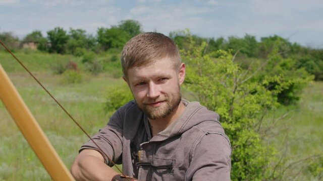 a young guy shoots a bow at a target, in nature, and hits the target, the arrow pierces the target for flight, pulls the bowstring tightly for a shot. Prores 422