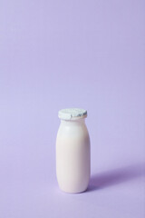 Bottles with probiotics and prebiotics dairy drink on light purple background.