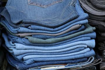 selective focus, pile of folded jeans on shelf. Jeans portrait in different colors